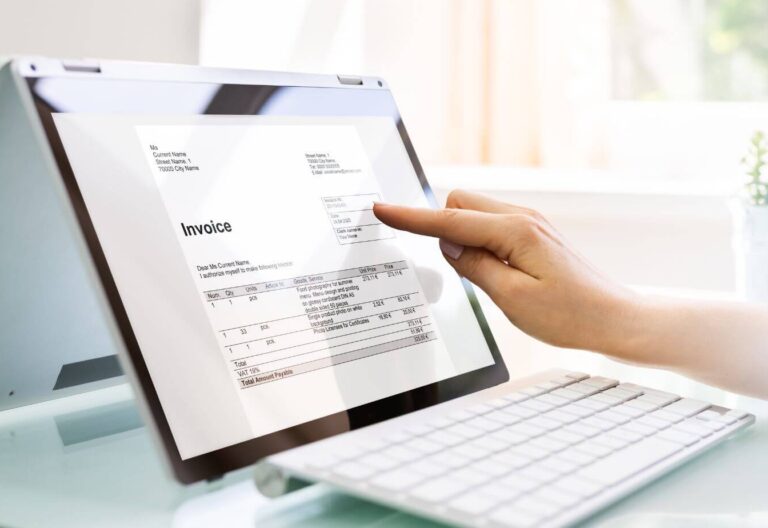 Hand tippt auf Tablet, Aufschrift Invoice, Rechnungen digitalisieren